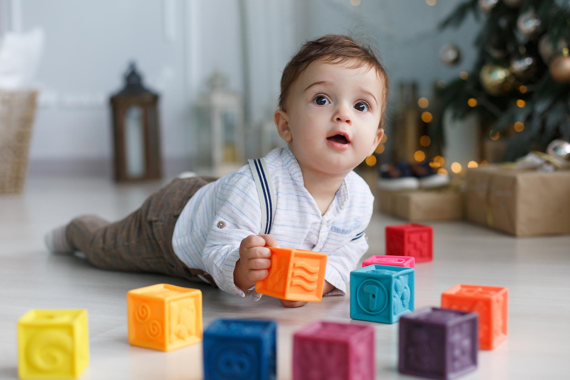 A baby sitting with colourful building blocks.