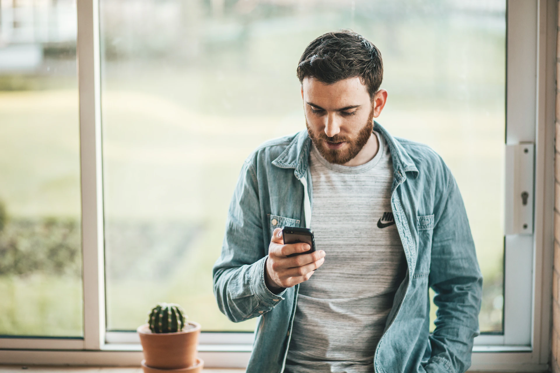 An adult looking at a phone outdoors.