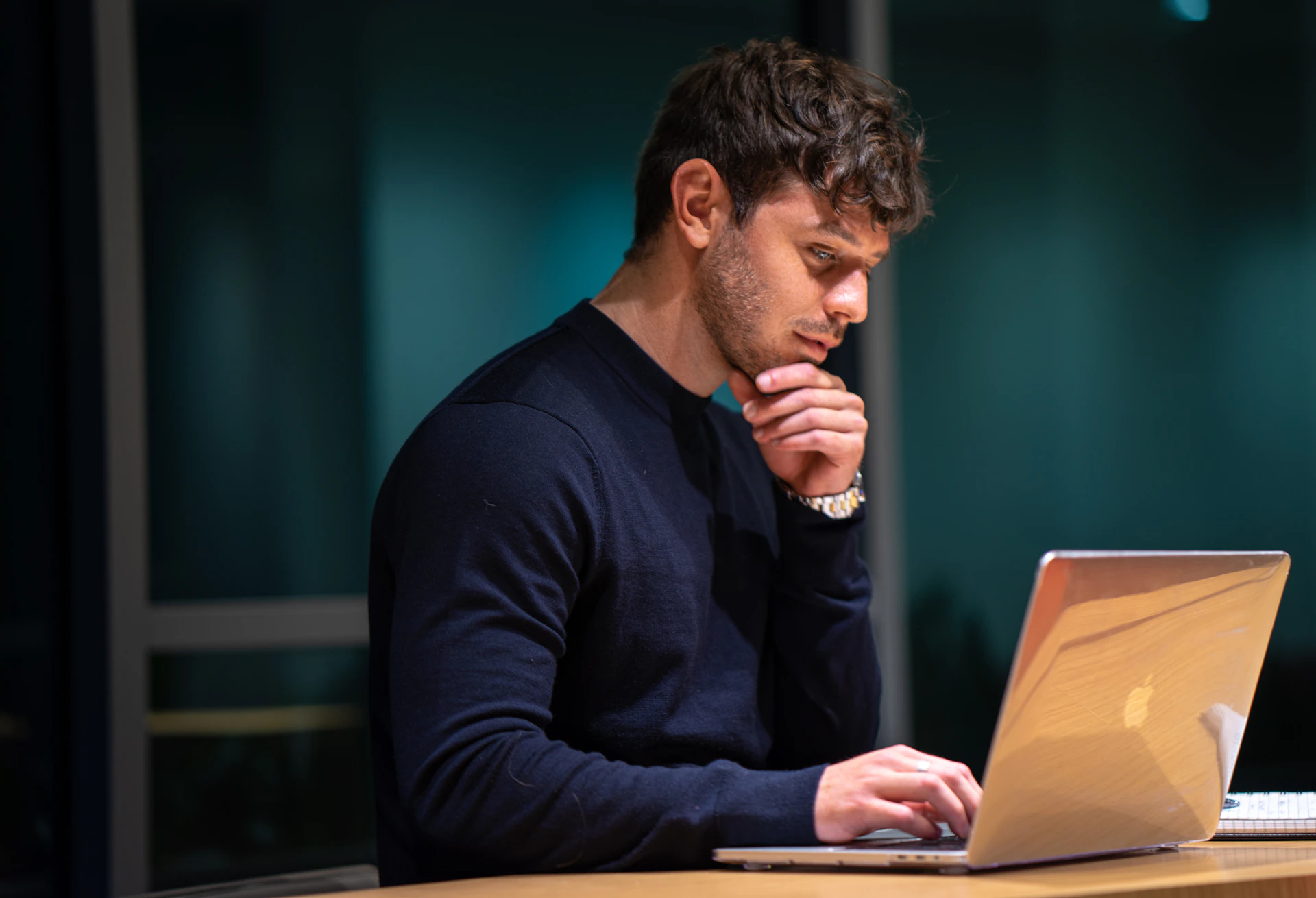 An adult considering information on a laptop.